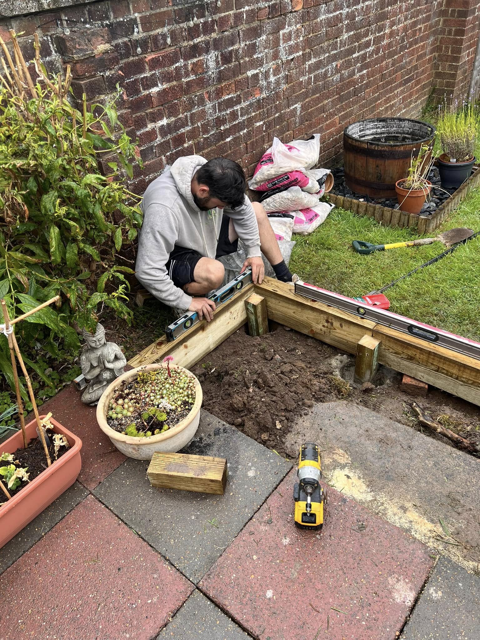 Contact Raymond Landscaping, Oliver working on patio edging ensuring border is level