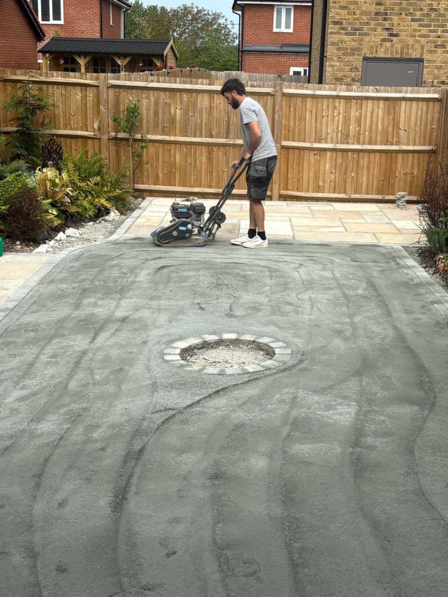 Oliver Raymond using a motorised ground tamping tool to flatten ground before installing patio slabs